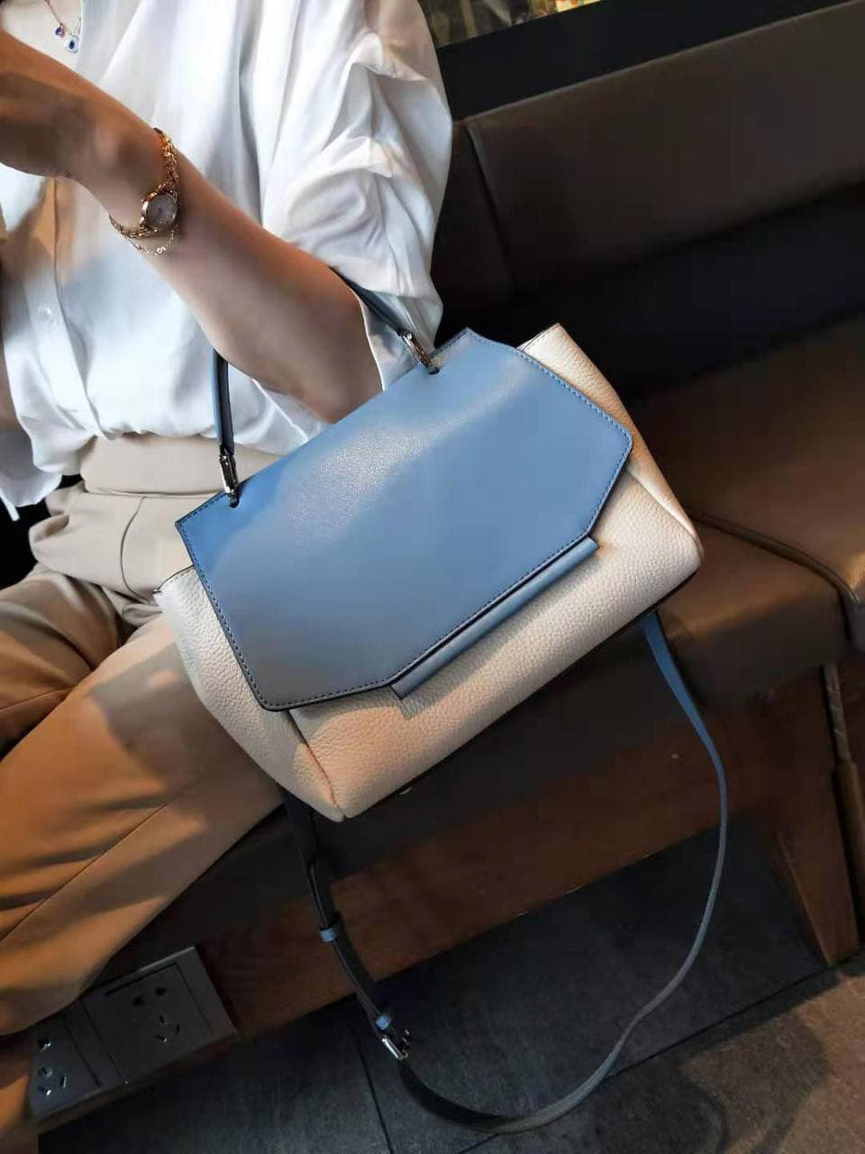 На фото 1 - Женская сумка сэтчел из натуральной кожи с фигурным клапаном, цвет молочный с синим